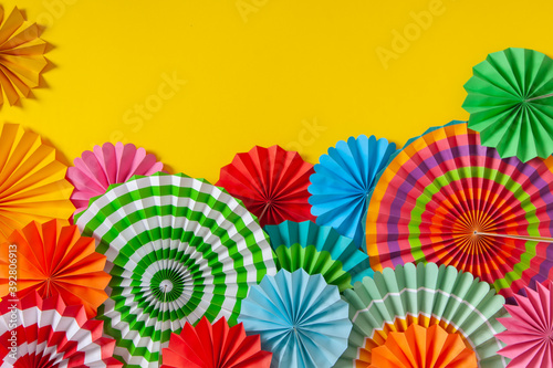 Colorful paper rosette and birthday garlands. Decorating for a party. Round  bright and color decoration. Yellow background.