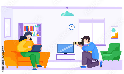 Professional young photographer makes pictures of a girl sitting on the sofa with a laptop. Guy with the camera takes pictures of the female freelancer. A photo session of the smiling woman