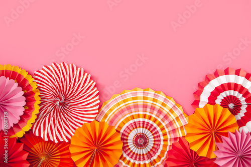 Colorful paper rosette and birthday garlands. Decorating for a party. Round  bright and color decoration. Pink background.