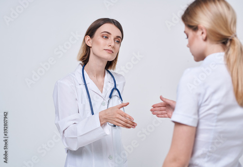 Professional doctor woman shakes hand of a female patient on a light background