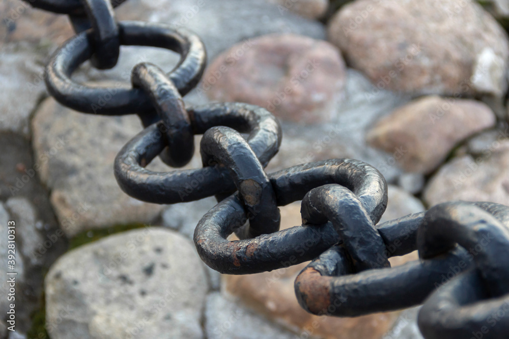 Old forged rusty chain with peeling paint on the background of paving stones. Old forged rusty chain with peeling paint on the background of paving stones.