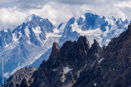 Beautiful panorama of high rocky mountains with mighty glaciers and snowy peaks against the blue sky and clouds © ParamePrizma