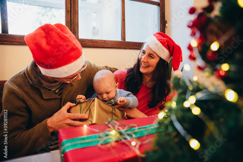 Happy family in private home with little child unwrap the Christmas gifts the Xmas day - Mother and father with boy having fun and smiling together photo