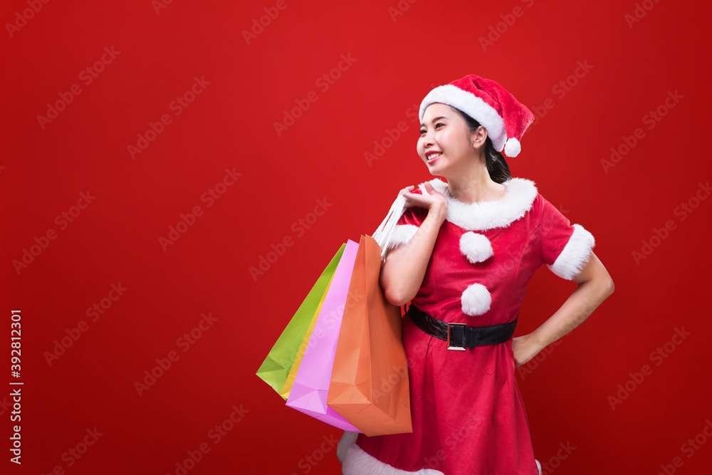 A beautiful woman in Santa Claus costume holding shopping bags on occasion of the Merry Christmas and Happy New Year A beautiful woman in Santa Claus costume holding shopping bags on occasion of the Merry Christmas and Happy New Year