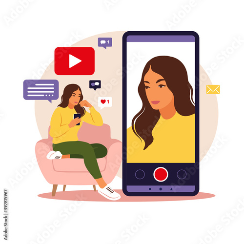 Woman video blogger sitting on sofa with phone and recording video with smartphone. Different social media icons. Vector illustration in flat style.