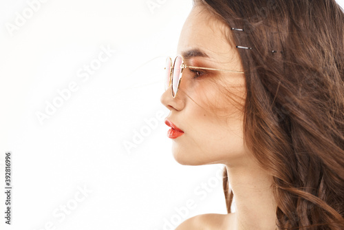 Portrait of brunette woman in sunglasses naked shoulders light background