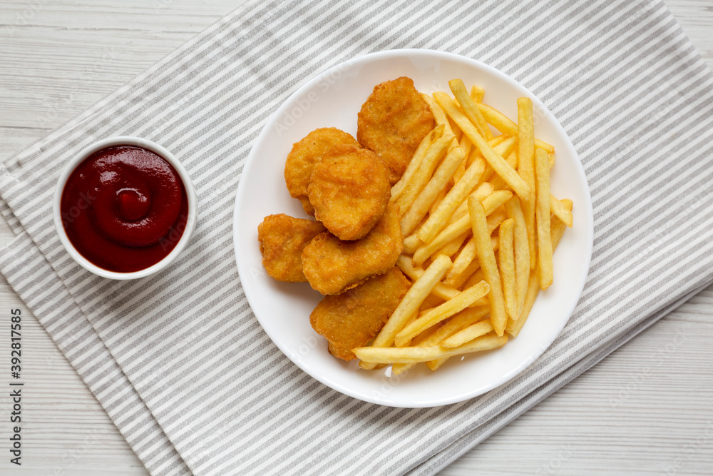 Tasty Fastfood: Chicken Nuggets and French Fries on a plate on a white wooden table, top view. Flat lay, overhead, from above. Tasty Fastfood: Chicken Nuggets and French Fries on a plate on a white wooden table, top view. Flat lay, overhead, from above.