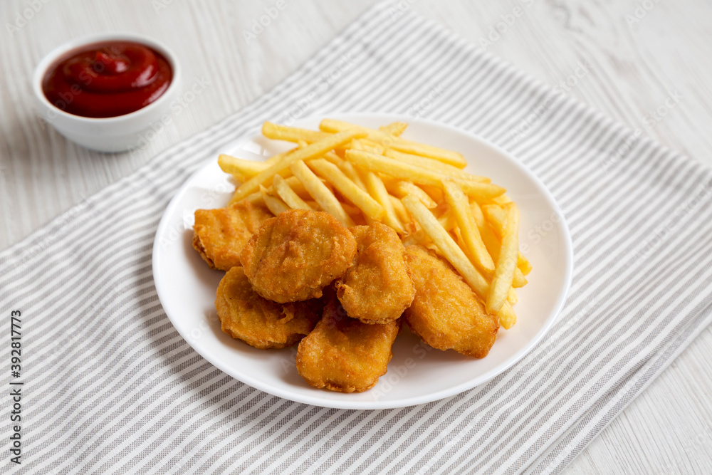 Tasty Fastfood: Chicken Nuggets and French Fries on a plate on a white wooden background, side view. Tasty Fastfood: Chicken Nuggets and French Fries on a plate on a white wooden background, side view.