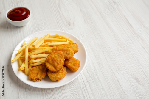 Tasty Fastfood: Chicken Nuggets and French Fries on a plate on a white wooden background, low angle view. Copy space.