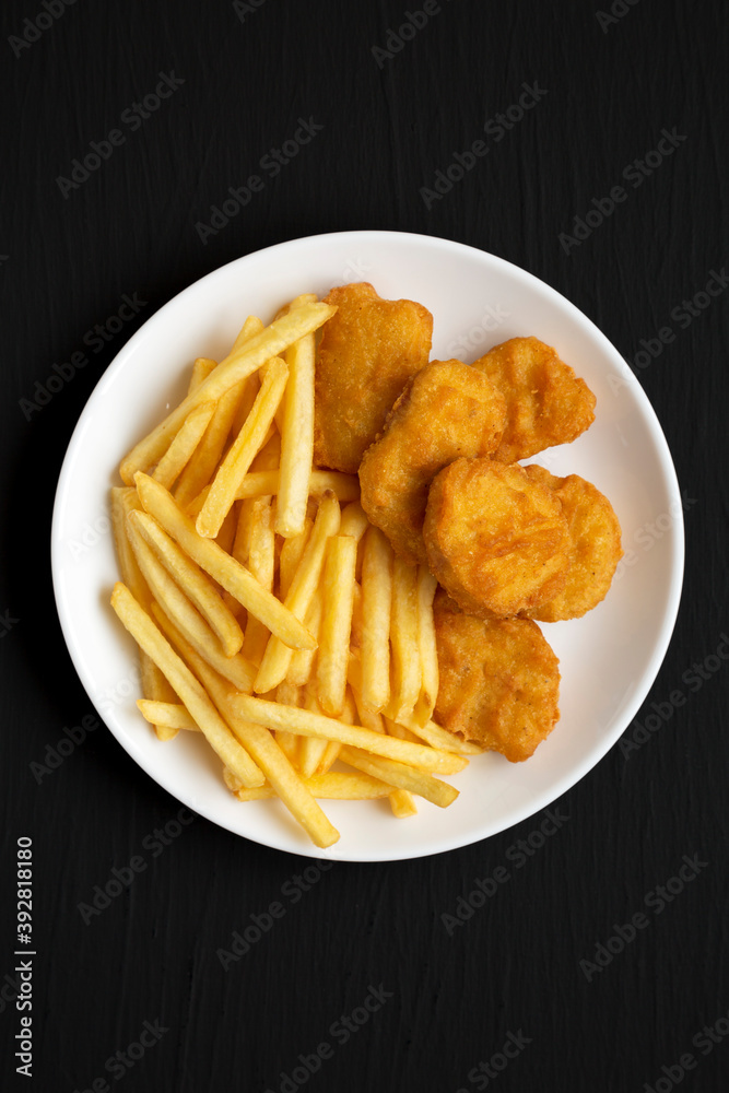 Tasty Fastfood: Chicken Nuggets and French Fries on a plate on a black background, top view. Flat lay, overhead, from above. Tasty Fastfood: Chicken Nuggets and French Fries on a plate on a black background, top view. Flat lay, overhead, from above.