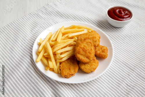 Tasty Fastfood: Chicken Nuggets and French Fries on a plate on cloth, low angle view.