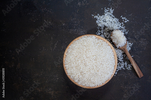 white rice (Thai Jasmine rice) in wooden bowl on dark wood background