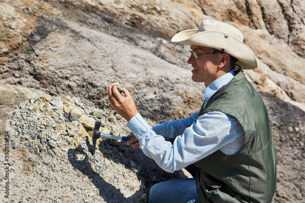 man geologist examines a rock sample in a desert area