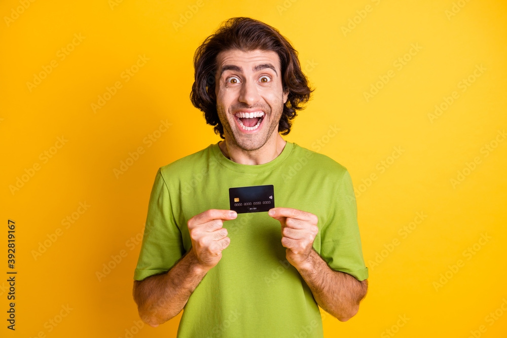 Portrait photo of happy man showing bank plastic card smiling isolated on vibrant yellow color background Portrait photo of happy man showing bank plastic card smiling isolated on vibrant yellow color background