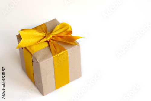 Gift box wrapped by kraft brown paper with beautiful yellow satin ribbon. Universal gifts design for all kind of celebration