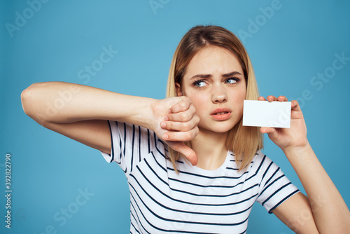 Woman with a business card in her hands a striped T-shirt blue background Copy Space © SHOTPRIME STUDIO