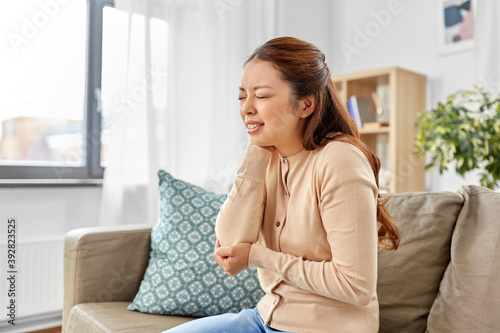 people, health and problem concept - unhappy asian woman suffering from ache in hand at home