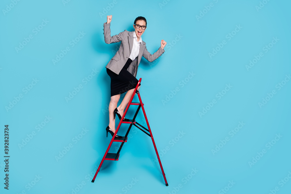 Fototapeta premium Full length photo agent girl climb career ladder raise fists scream wear jacket skirt isolated blue color background