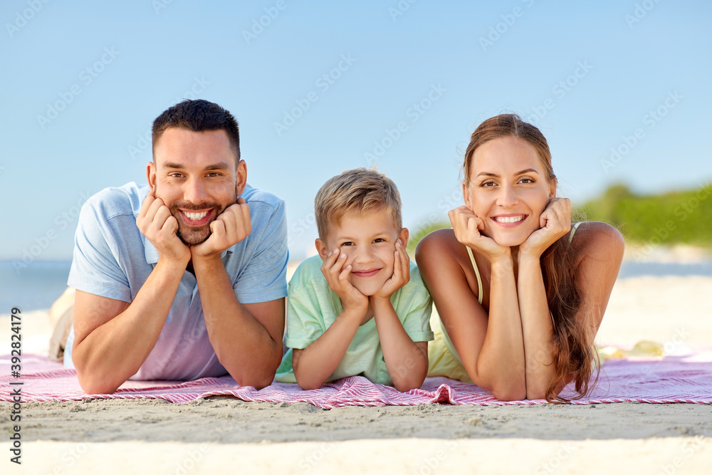 family, leisure and people concept - happy mother, father and little son lying on summer beach family, leisure and people concept - happy mother, father and little son lying on summer beach