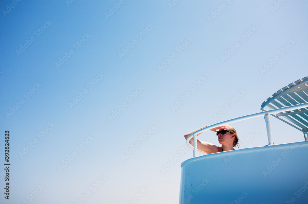 Obraz premium Young woman looking out from a boat on a clear summer day.