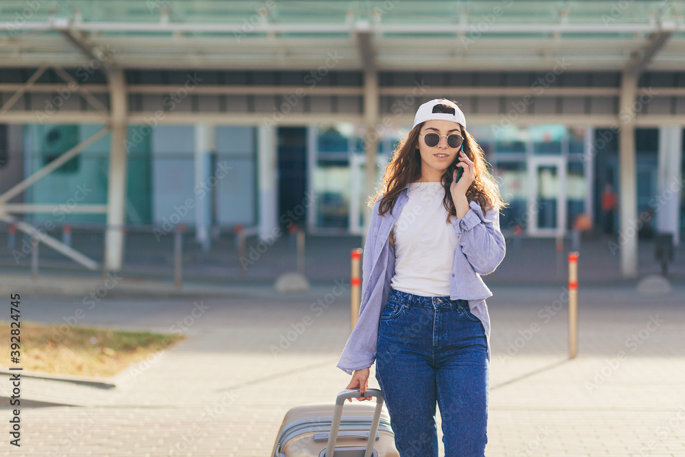 Fototapeta premium A young beautiful girl student leaves the airport in a new city, and waits for a taxi