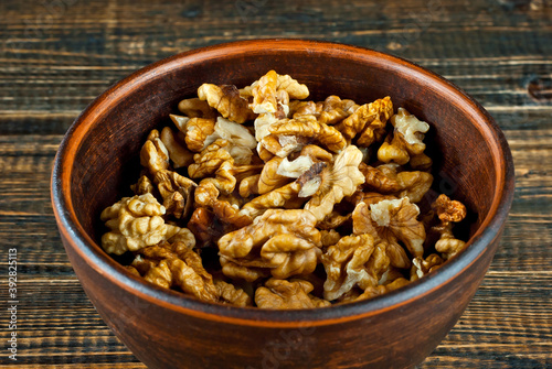 Peeled walnuts in a bowl. Nuts close up on an old wooden board. Food on a shabby table.