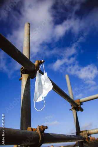 a coronavirus facemask hanging on some scaffolding on a construction building site