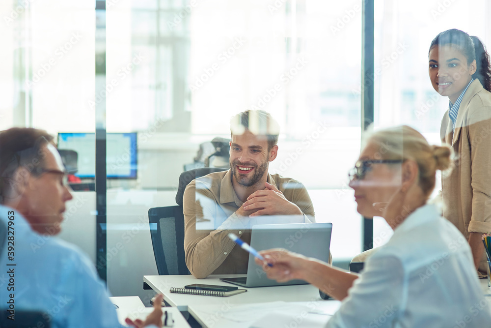 Group of multiracial business people sitting in board room in the modern office and discussing something while having a meeting Group of multiracial business people sitting in board room in the modern office and discussing something while having a meeting