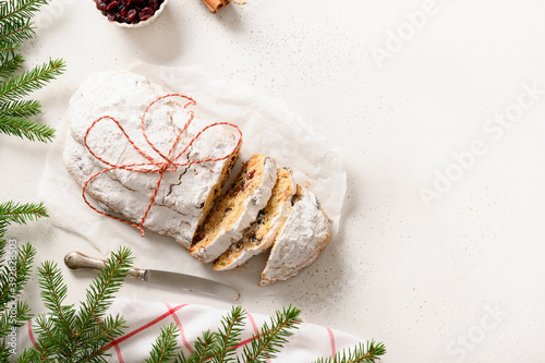 Christmas cutted stollen with candied fruit on white table. Tasty traditional German treats. Copy space. View from above, photo