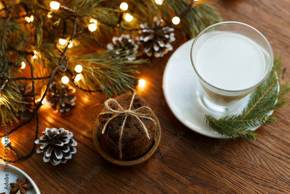 From above view of fresh milk in glass and stack of sweet cookies prepared for Santa Claus at home on wooden table with Christmas decorations From above view of fresh milk in glass and stack of sweet cookies prepared for Santa Claus at home on wooden table with Christmas decorations