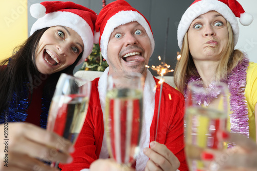 Man and two women rejoice and celebrate Christmas. New Year holidays and corporate parties concept