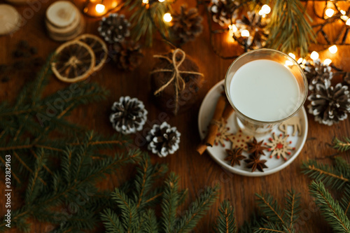 Delicious milk in glass and stack of chocolate cookies on wooden table with Christmas decorations prepared for Santa at home  © Dzmitry