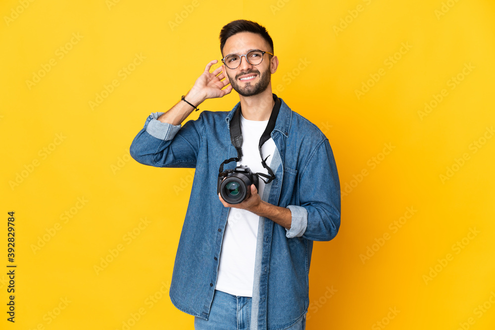 Young photographer girl isolated on yellow background having doubts Young photographer girl isolated on yellow background having doubts