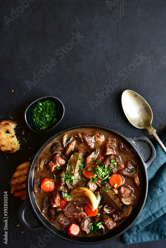 Beef bourguignon - meat stew with vegetables and mushrooms with red wine, traditinal dish of french cuisine. Top view with copy space.