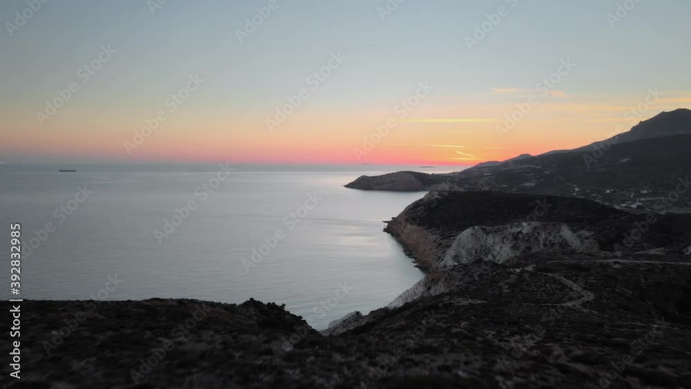Aerial shot revealing the coastline of Milos Island behind a hill just after sunset Aerial shot revealing the coastline of Milos Island behind a hill just after sunset