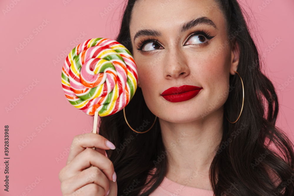 Pleased beautiful brunette girl posing with lollipop