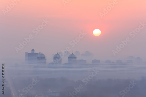 Blurred outlines of the city at dawn in smog

