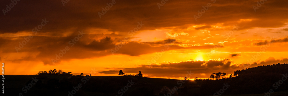 Panoramic orange sunset with silhouette of landscape