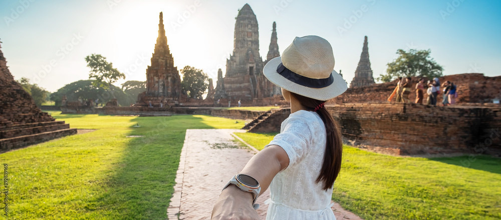 Tourist Woman in white dress holding her husband by hand and walking to ancient stupa in Wat Chaiwatthanaram temple in Ayutthaya Historical Park, summer, together, follow me, Asia and Thailand travel
