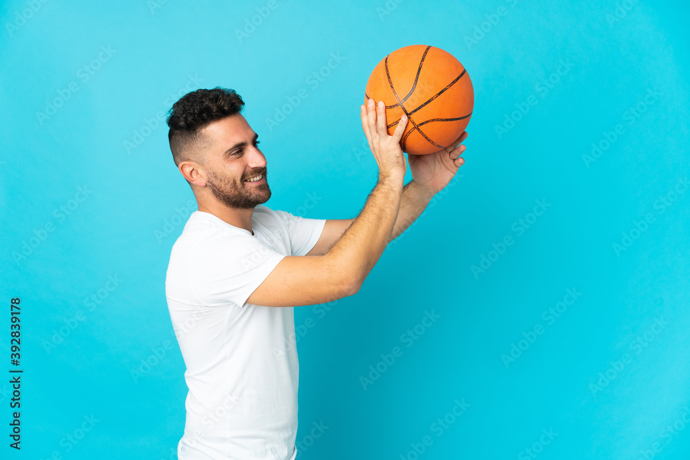 Caucasian man isolated on blue background playing basketball