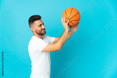 Caucasian man isolated on blue background playing basketball © luismolinero