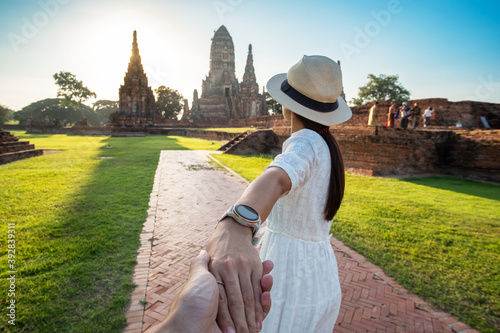 Photography Tourist Woman in white dress holding her husband by hand and walking to ancient