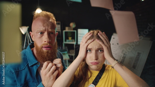 Upset young team arguing near idea board in office. Couple despairing near board