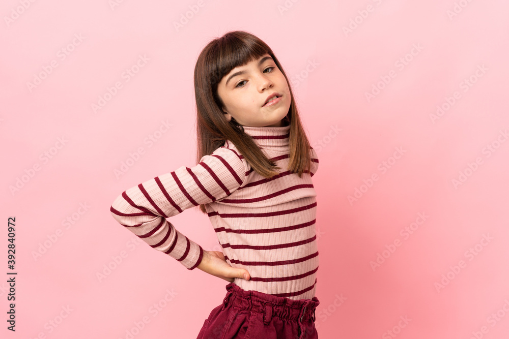 Little girl isolated on pink background suffering from backache for having made an effort Little girl isolated on pink background suffering from backache for having made an effort