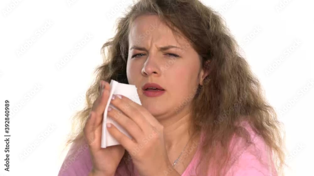 portrait of a young sick woman with curly hair has an itchy nose and sneezes on a white background portrait of a young sick woman with curly hair has an itchy nose and sneezes on a white background