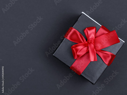 gift box with ribbon. Gift box with a red ribbon on the right on a black background with a place for text on the left, top view close-up. 