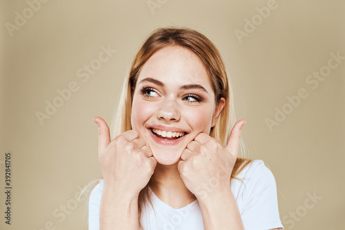 Cheerful woman in a white T-shirt gestures with her hands emotions beige background