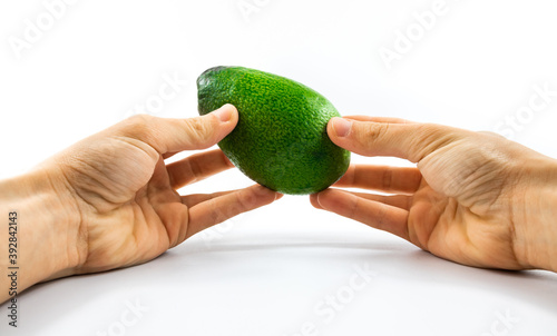 Man carefully holds an avocado in two hands on a white isolated background, template for the site