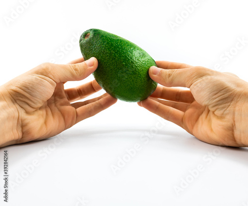 Man carefully holds an avocado in two hands on a white isolated background, template for the site