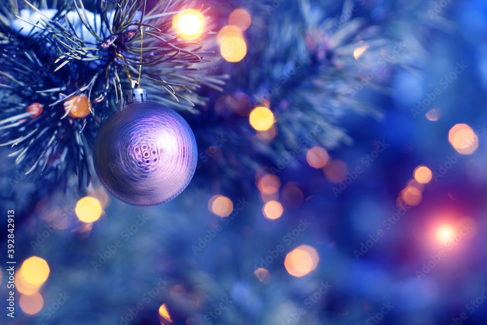 Fototapeta premium Blurred festive Christmas background. Pine branch with balls close-up, blurry bokeh lights, snowflakes.
